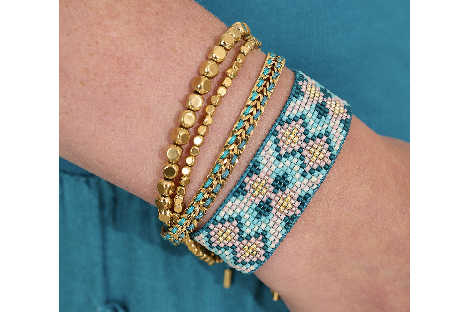 Cari Teal Gold Braided Bracelet styled on the wrist, evoking hidden lagoons with woven turquoise and navy threads, perfect for summer adventures and beach days.